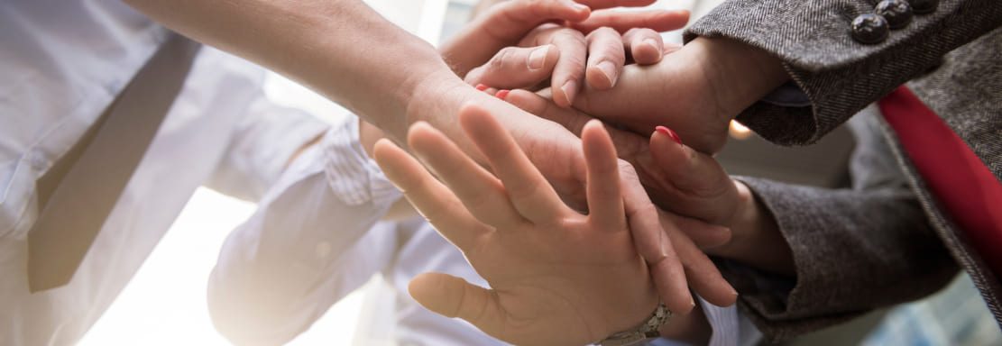 Manos unidas que representan la misión institucional basada en el compromiso y el trabajo en equipo