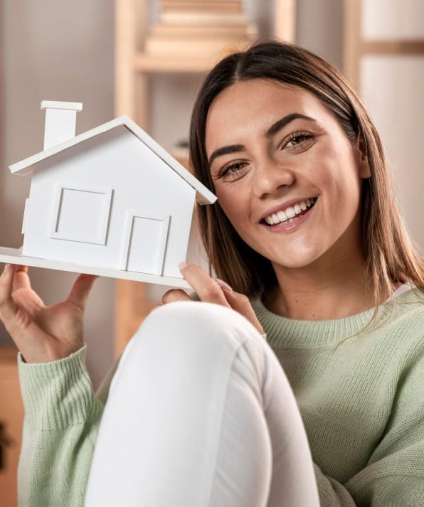 Mujer sosteniendo maqueta de casa como símbolo de beneficios y descuentos en vivienda